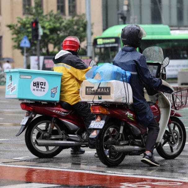 Two motorcyclists waiting for a green light at a Korean intersection. Media sourced from the Korea Herald.