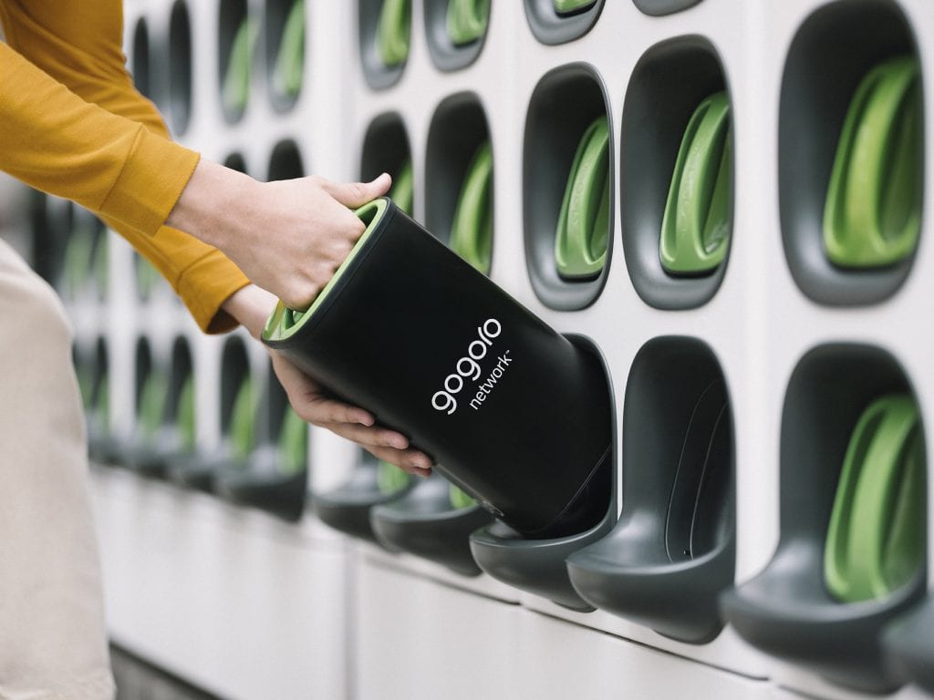 a hand removes a charged Gogoro battery in preparation to recharge an electric scooter.