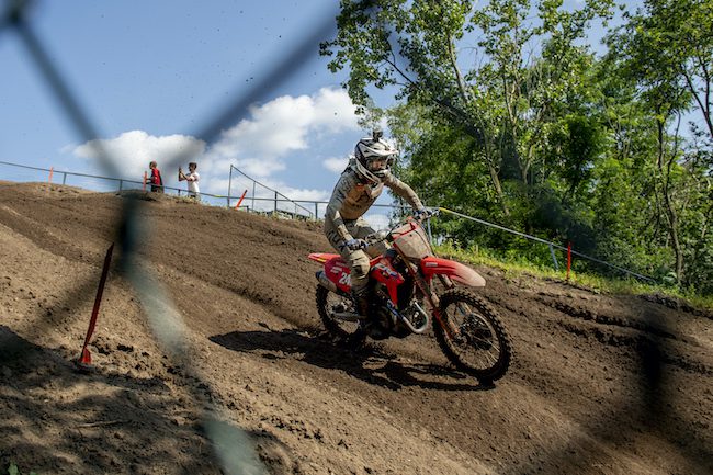 A racer from Team HRC racing down a dirt hill at the MXGP Championship
