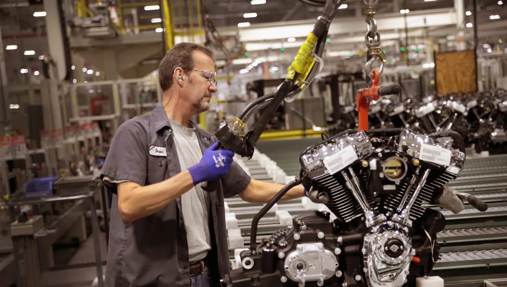 A worker in a Harley-Davidson production plant putting together a motorcycle engine. Photo courtesy of MBJ.