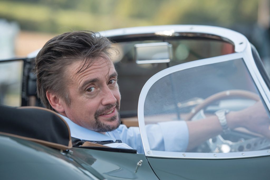 a view of Hammond on the Grand Tours show, in a car, turning around and smiling at the camera