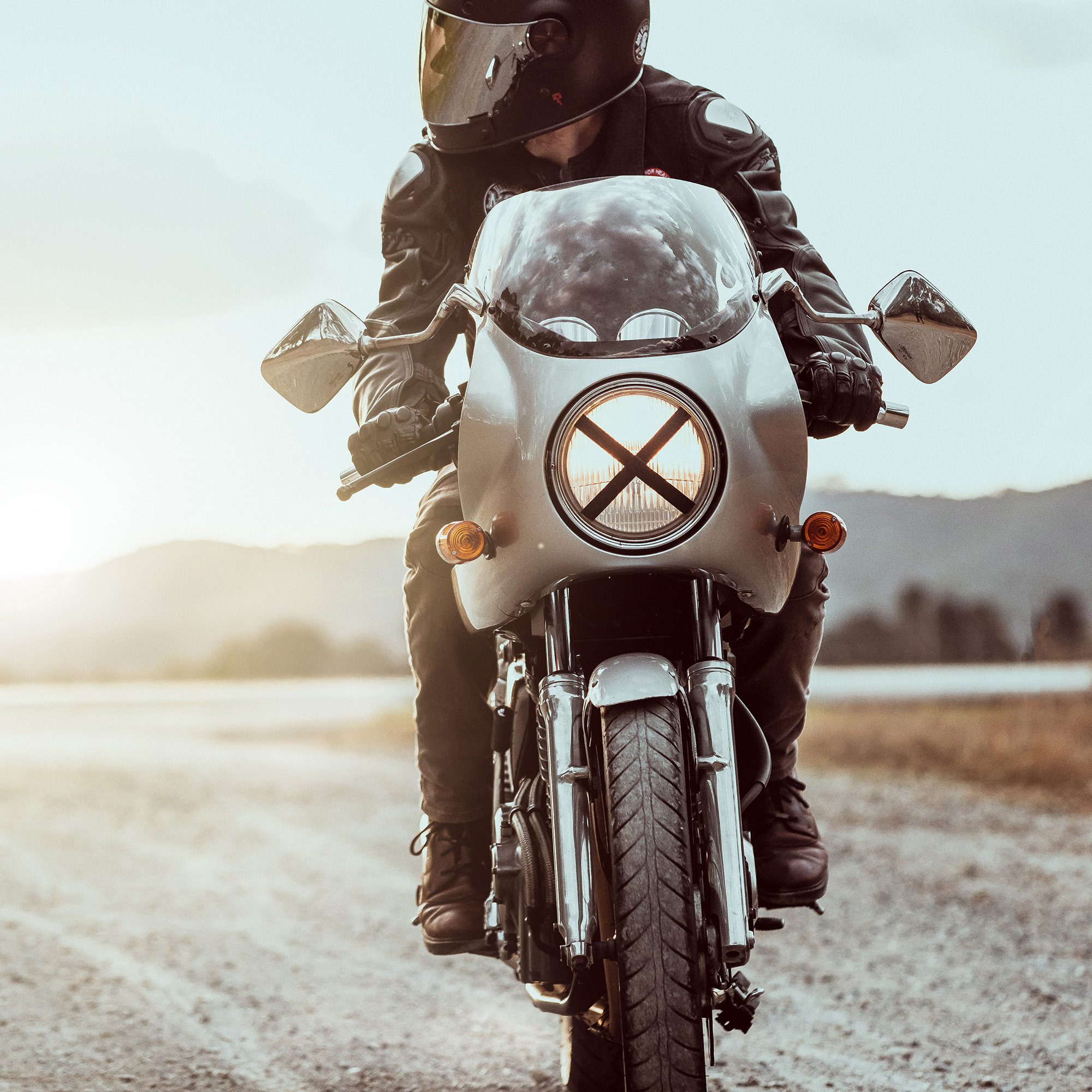 A cafe racer motorcycle and rider tackles a dirt road in Australia