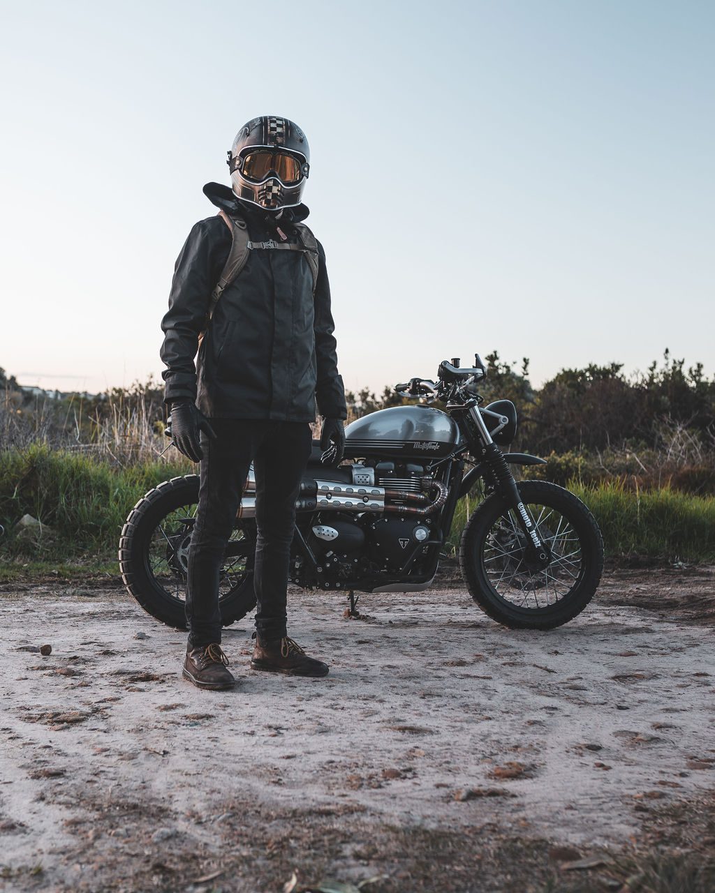 Motorcyclists and scrambler bike standing stationary on sand at dusk in Sydney