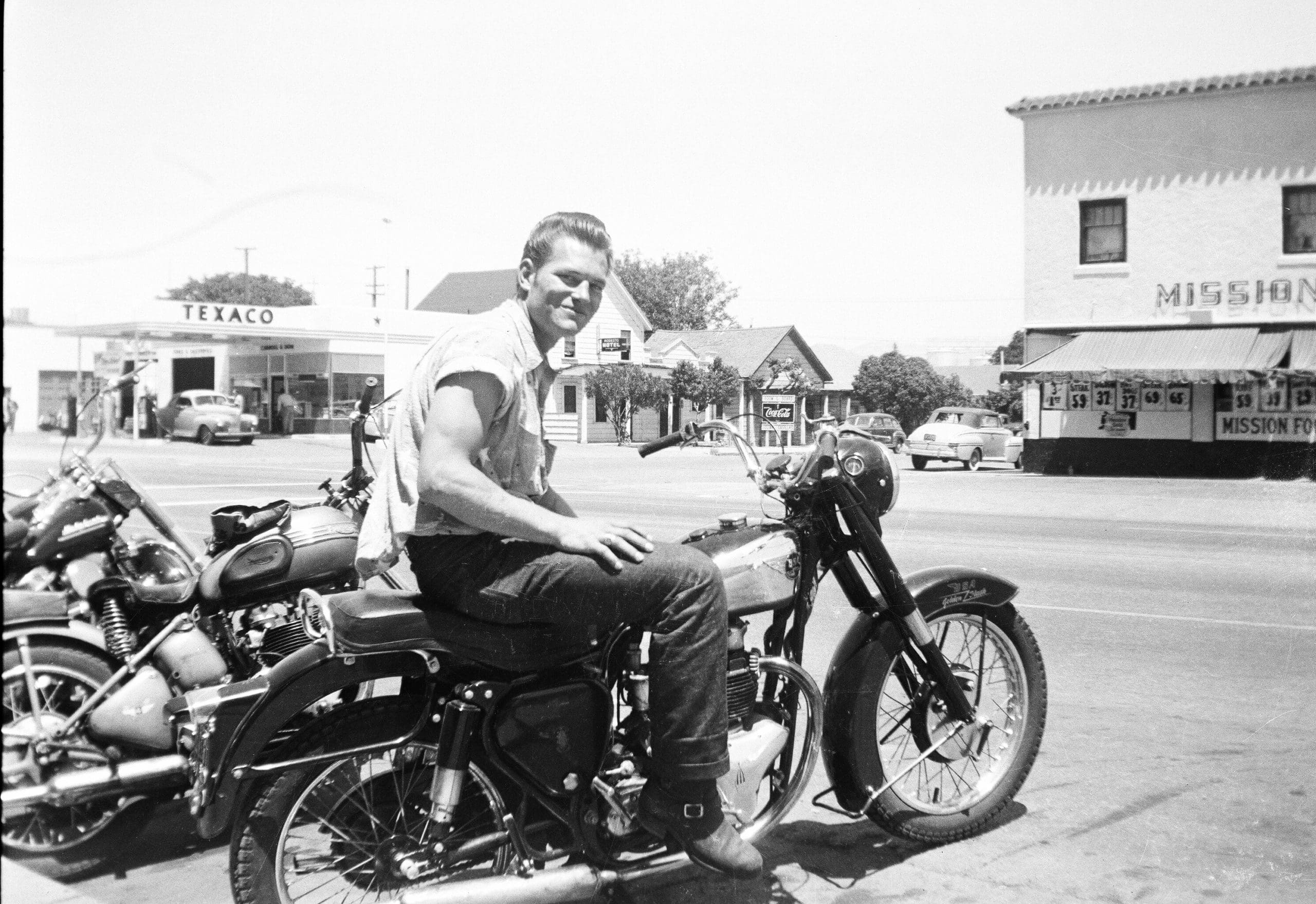 Two male riders pose for a photo on a street in Hollister, CA. in July 1947