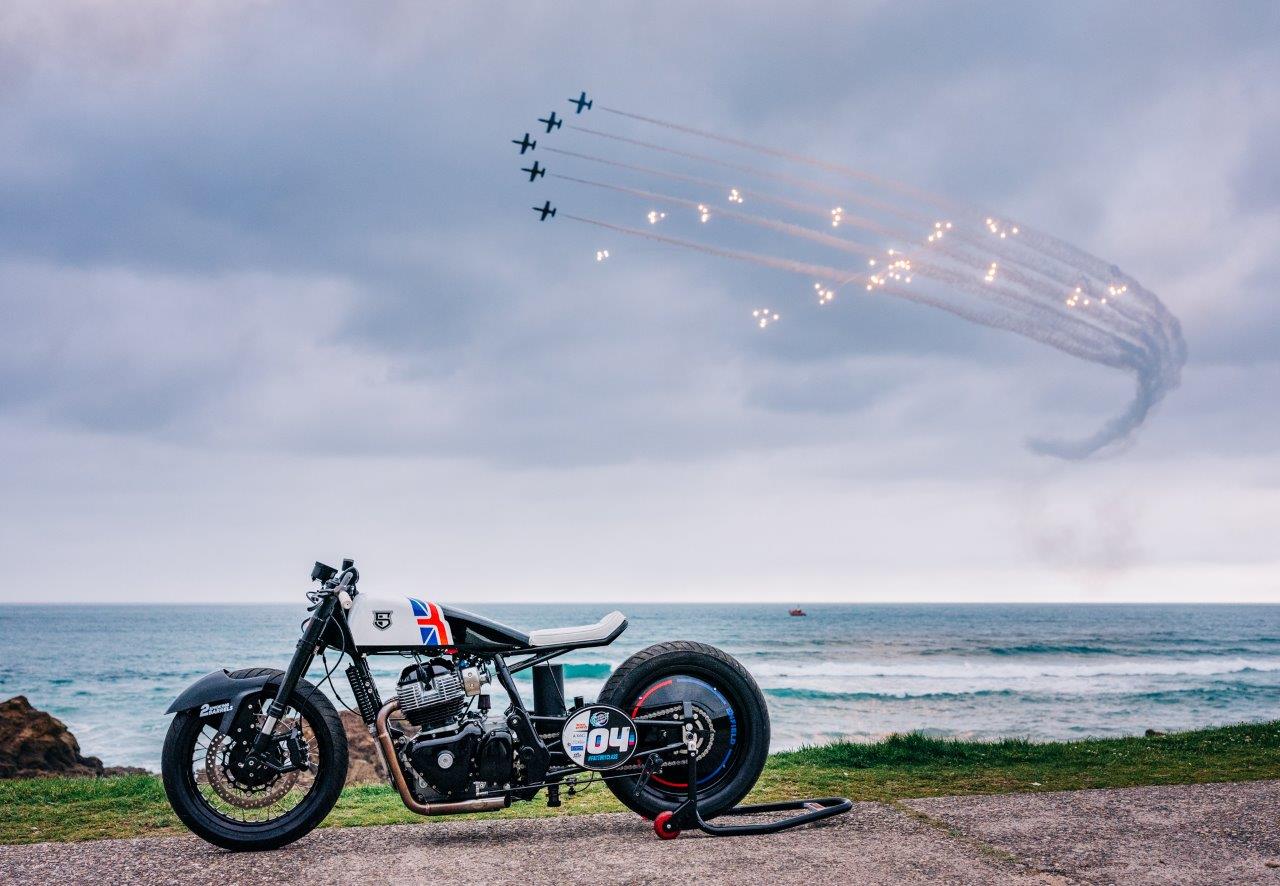 Royal Enfield sprint racing motorcycle on Biarritz beach with jet aircraft doing fly-by