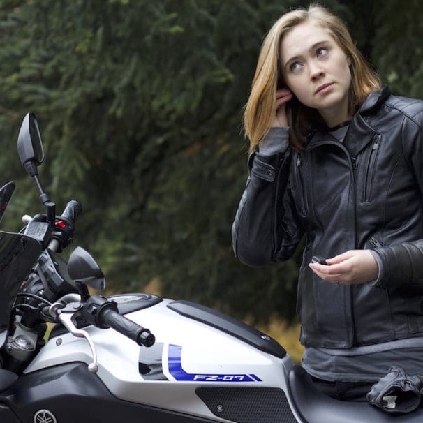 A woman installing earplugs before a ride. Media sourced from RideWell.