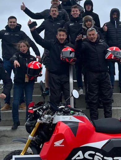 A view of the Acerbis team and their Honda Monkey, featuring a massive gas tank. Media sourced from Superbike News.