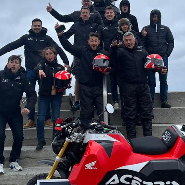 A view of the Acerbis team and their Honda Monkey, featuring a massive gas tank. Media sourced from Superbike News.