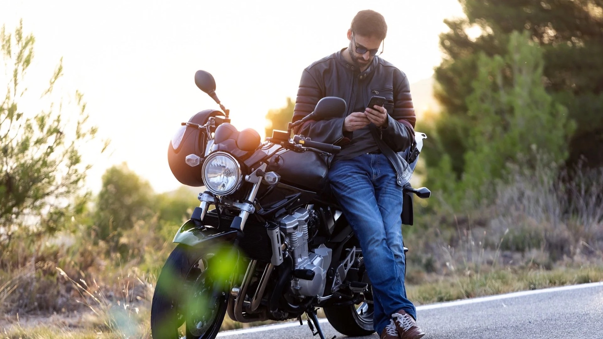 A motorcyclist checking his phone. Media sourced from The Drive.