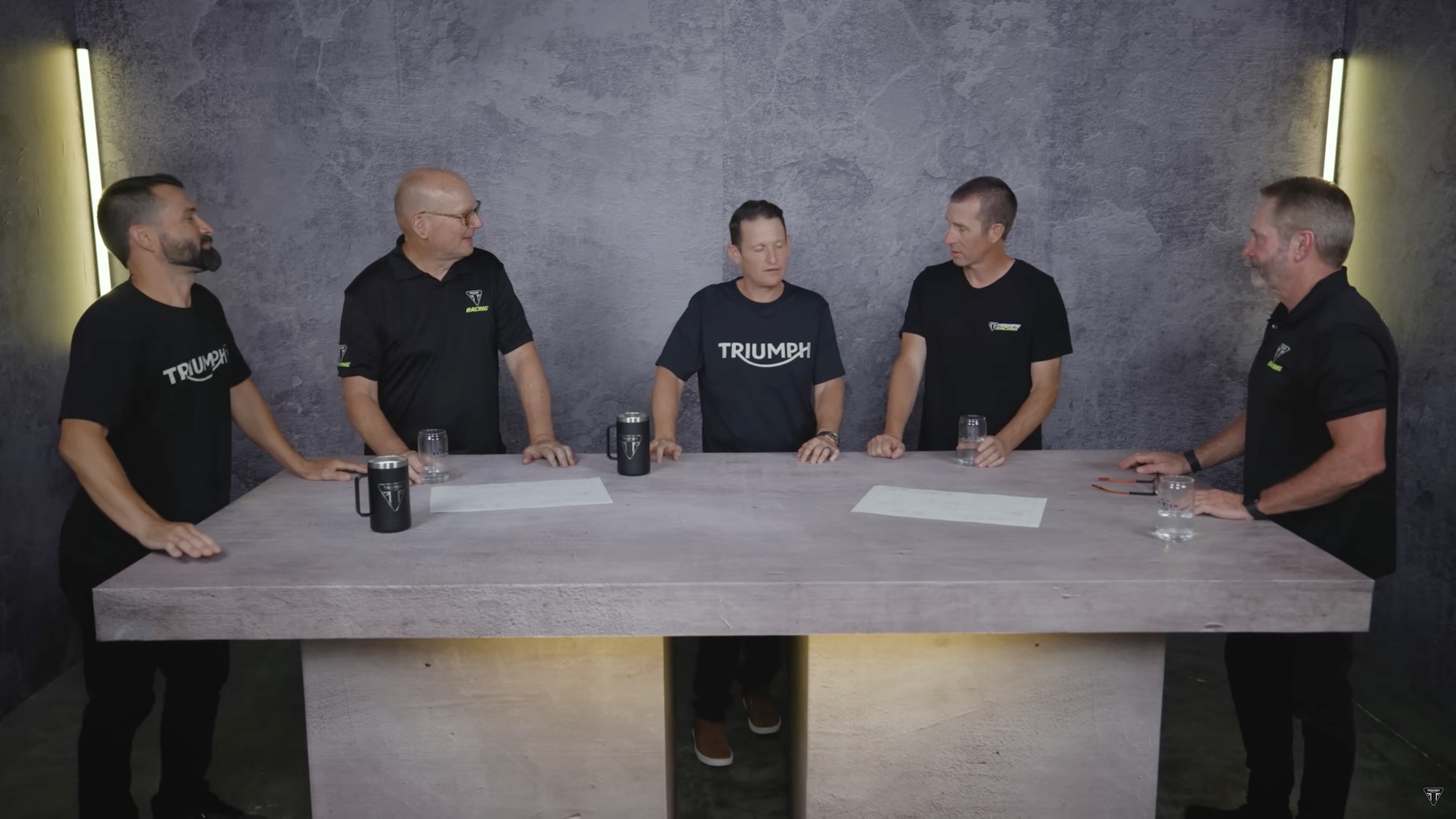 A view of Triumph's teaser, showing the frame for their incubating motocross machine and the hands that went into designing the thing. From left to right: Ivan Tedesco, Dave Arnold, Ricky Carmichael, Stephen Scuba Westfall and Bobby Hewitt.