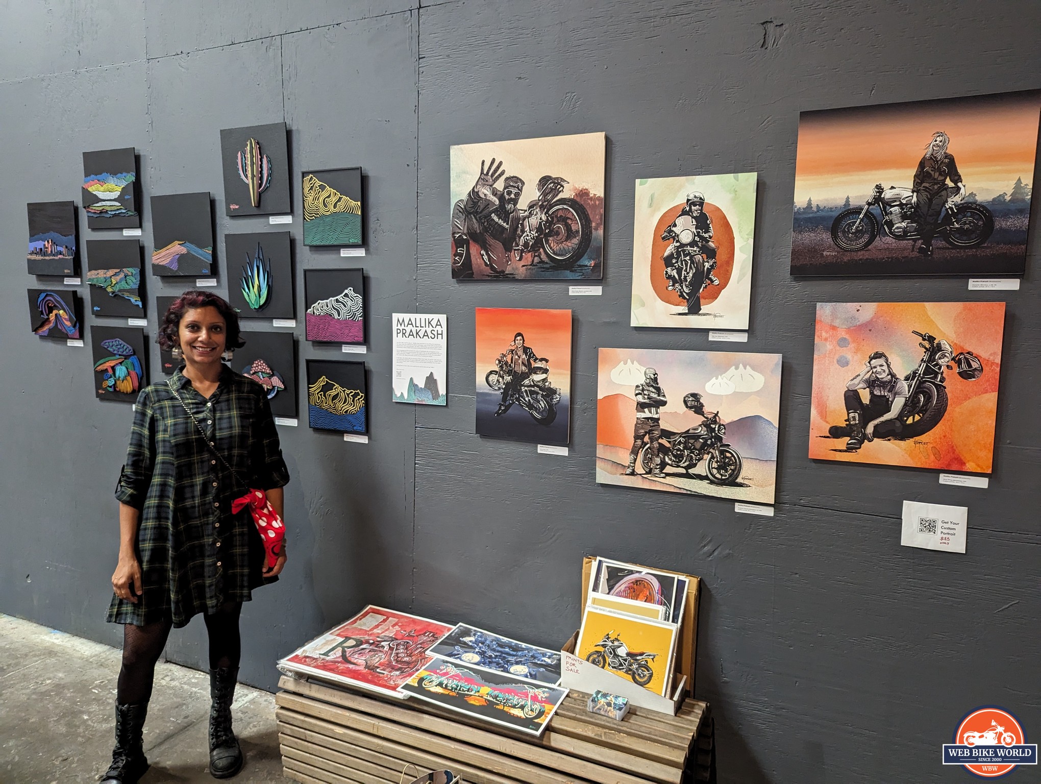 Millika Prakash standing in front of her artwork exhibit at the Women's Motorcycle Show 2023.