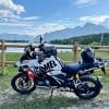 A BMW R1250GS with the Scorpion XT9000 seated on it by a lake.