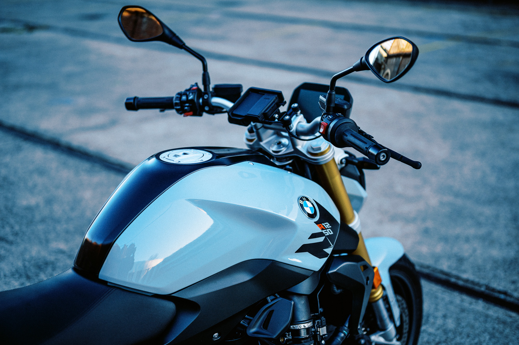 a detail photo of a 2023 BMW R 1250 R motorcycle at dusk in an old train carriage works