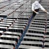 A view of a worker aligning a series of EV batteries. Media sourced from Energy Monitor.