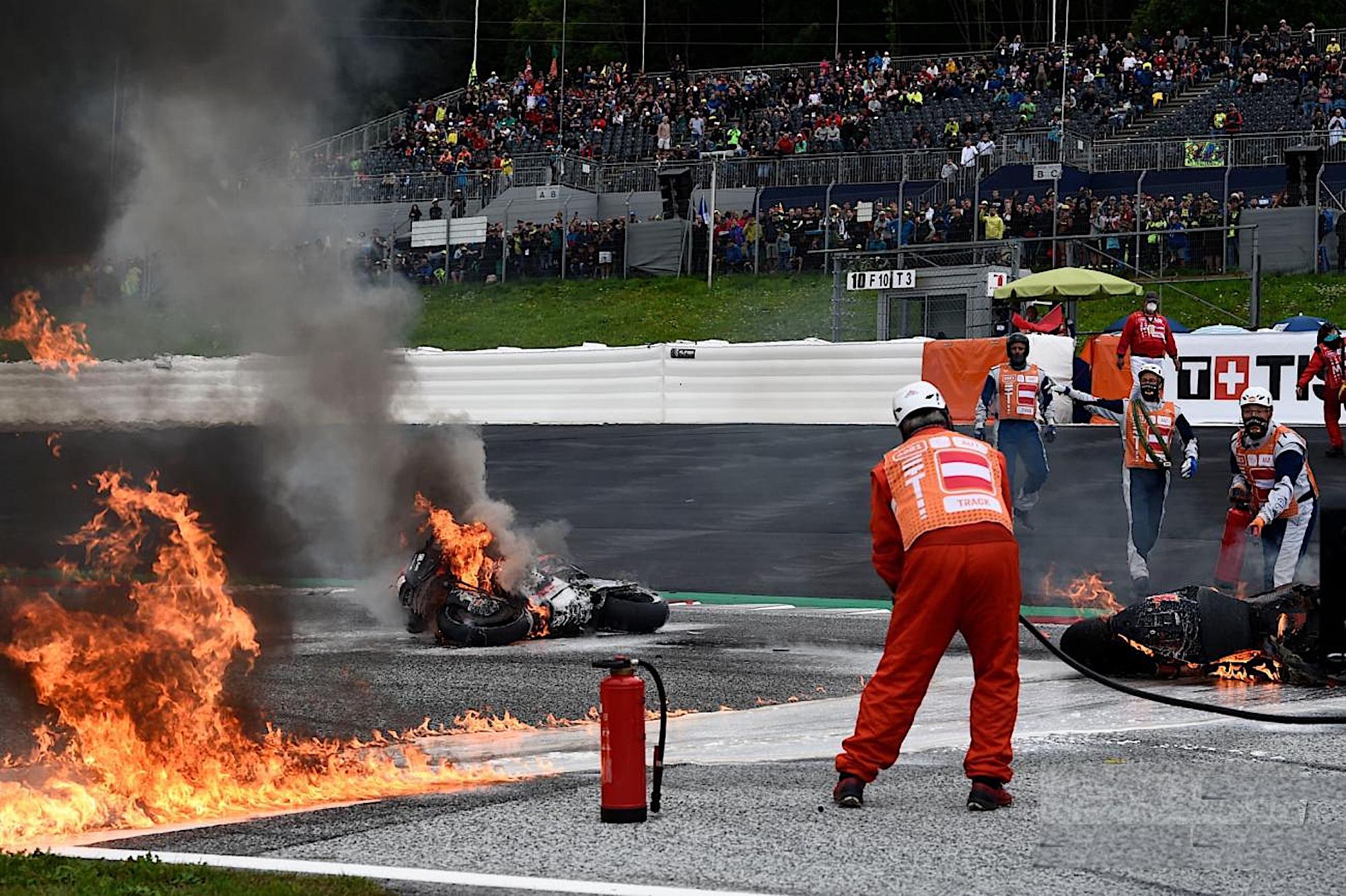 A team working to put out a fire on the MotoGP circuit. Media sourced from Crash, no pun intended.