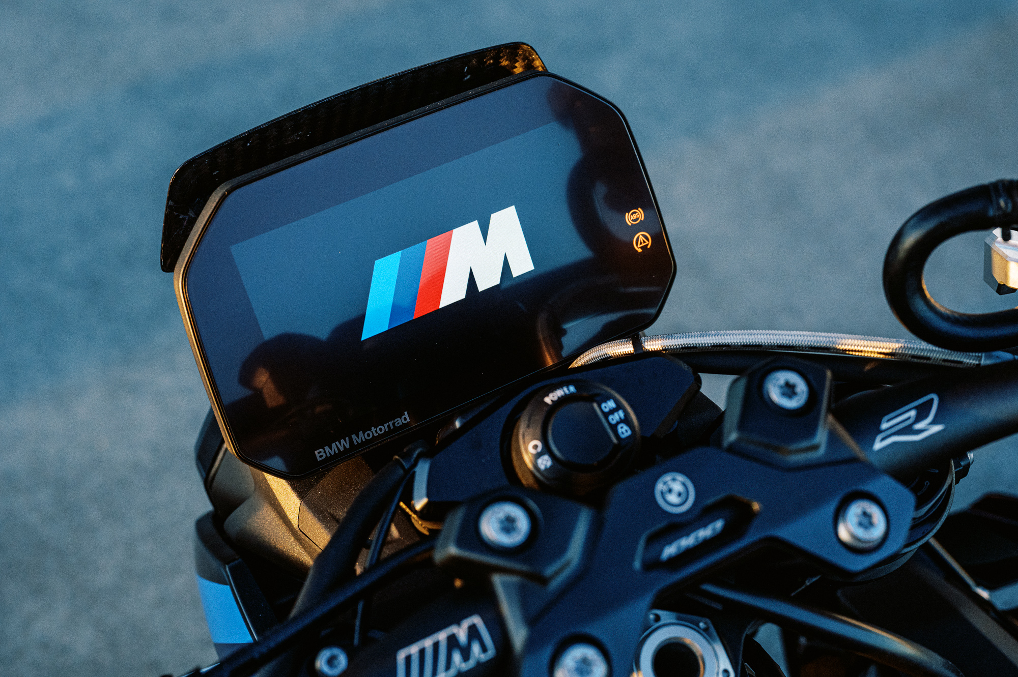 A detail shot of the 2023 BMW M 1000 R motorcycle on a rooftop car park at sunset