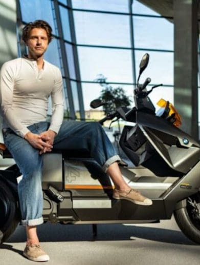BMW's new Design Director, Alexander Buchan, sitting on one of his designs, the CE 04. Media sourced from BMW.