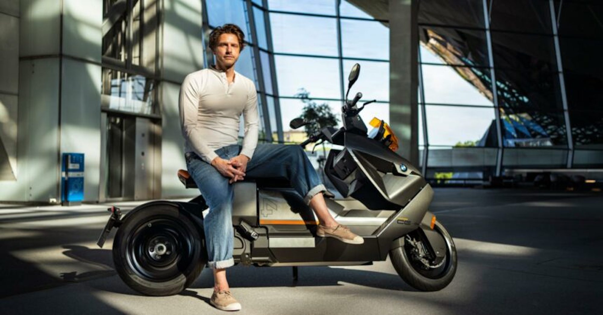 BMW's new Design Director, Alexander Buchan, sitting on one of his designs, the CE 04. Media sourced from BMW.