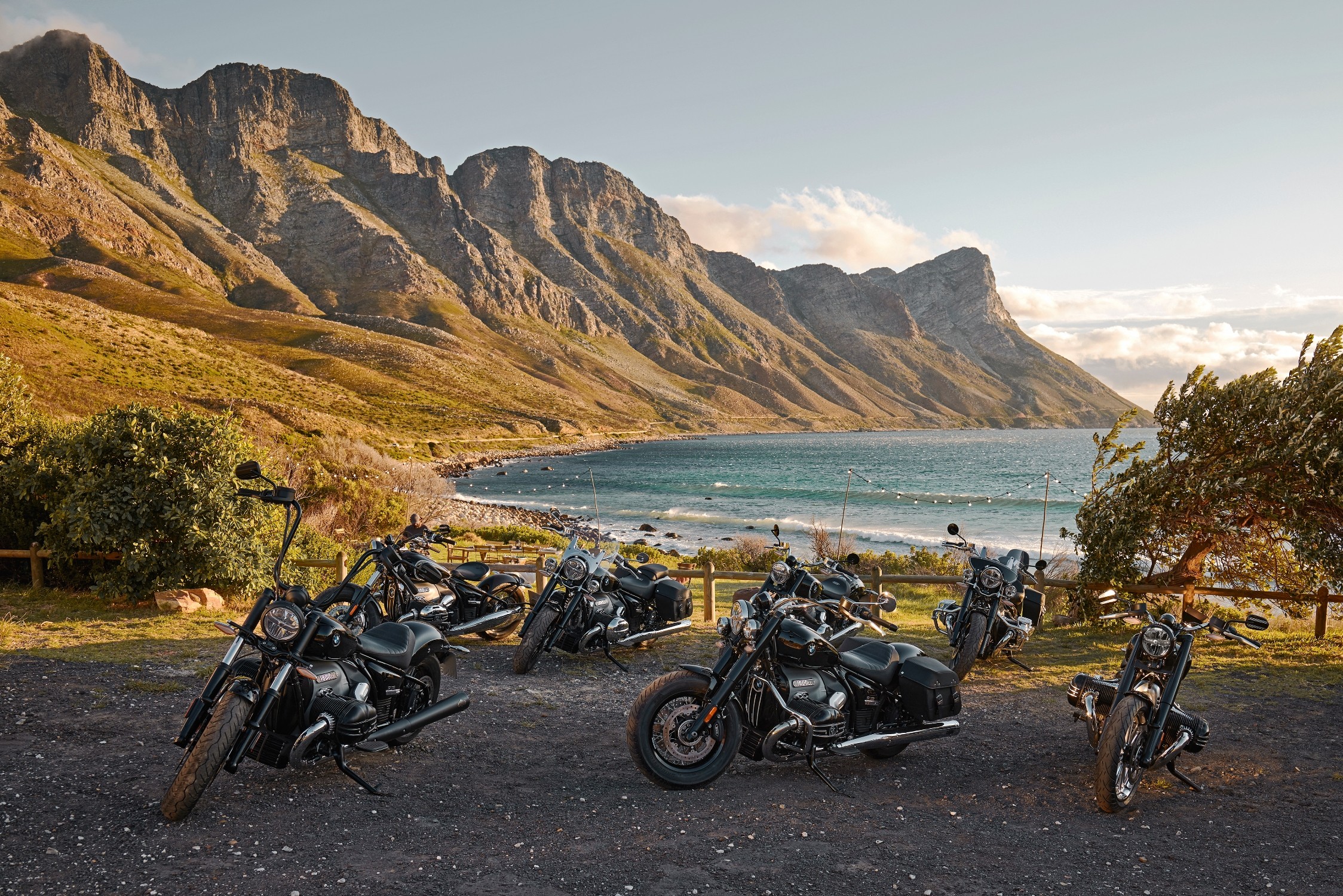 A group of 5 BMW R 18 motorcycles near the beach at sunset