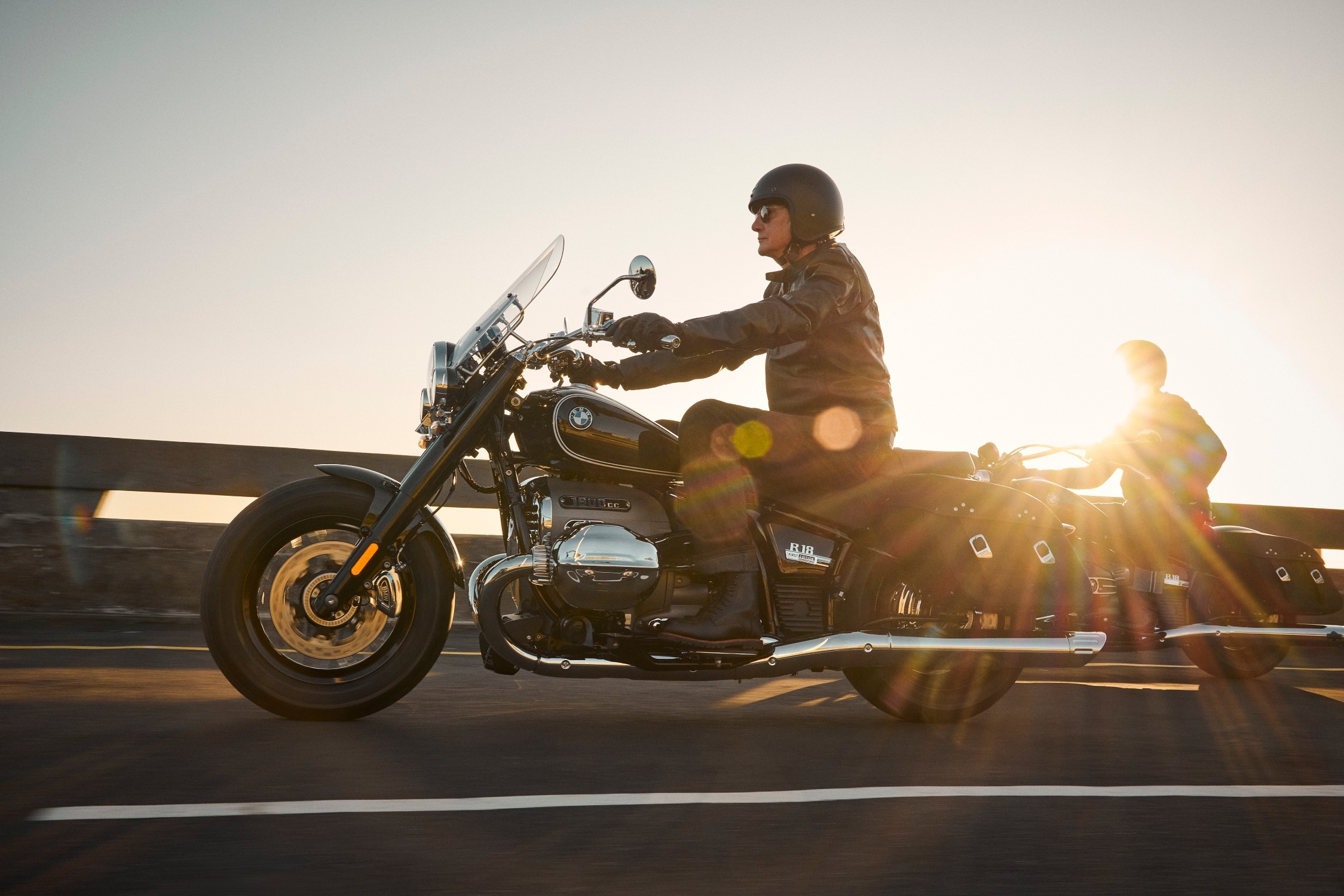 A man rides a BMW R 18 motorcycle at sunset