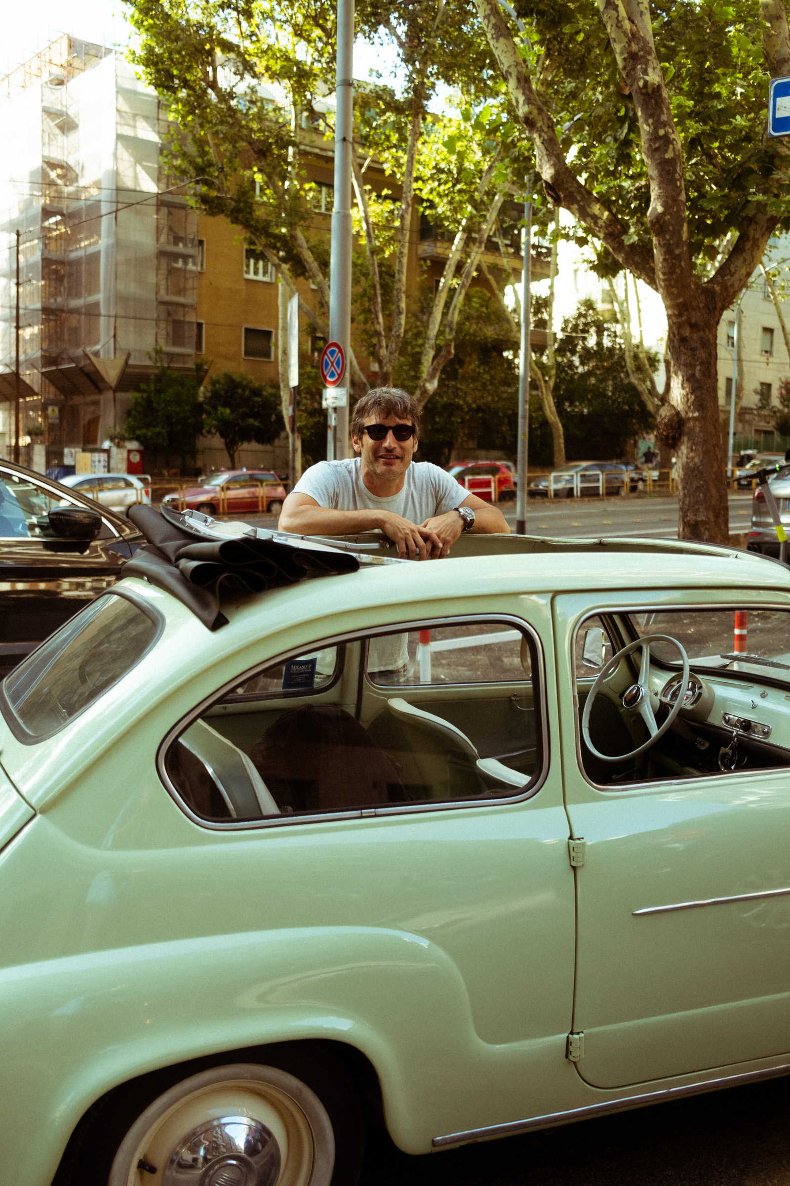 A man and his Fiat Seicento car parked on a Rome street