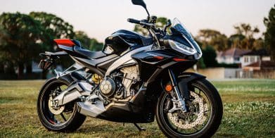 A 2023 Aprilia Tuono 660 Factory in a park at sunset.