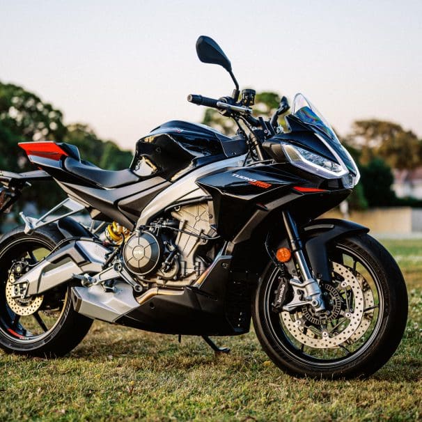 A 2023 Aprilia Tuono 660 Factory in a park at sunset.