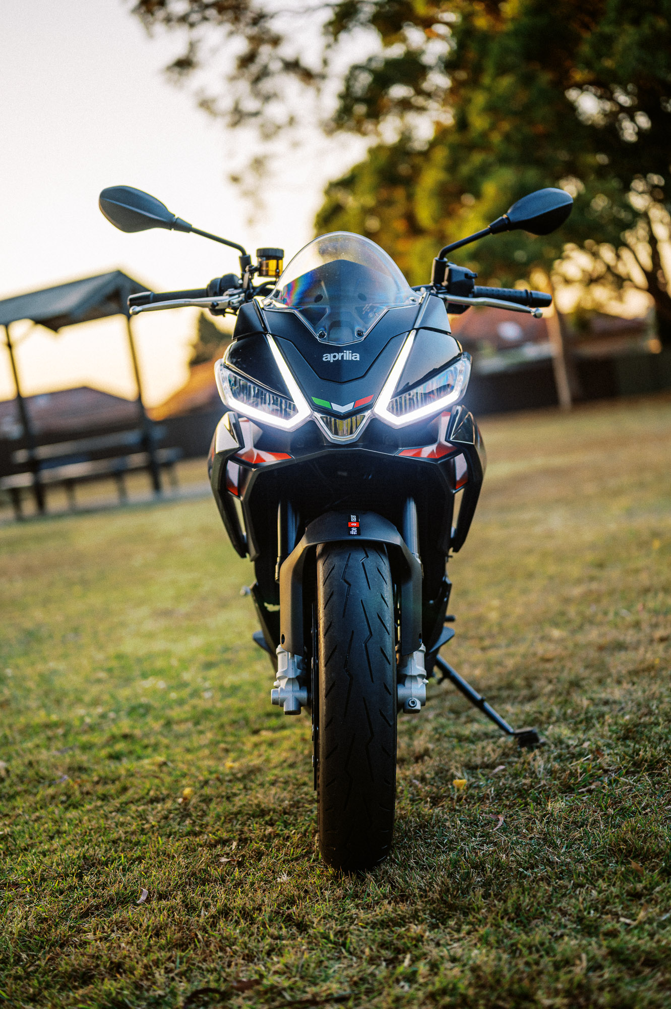 Detail shot of a 2023 Aprilia Tuono 660 Factory in a park at sunset
