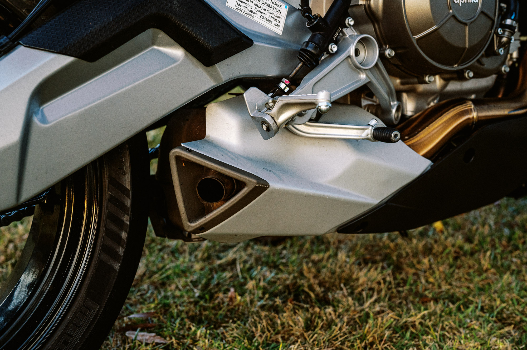 Detail shot of a 2023 Aprilia Tuono 660 Factory in a park at sunset