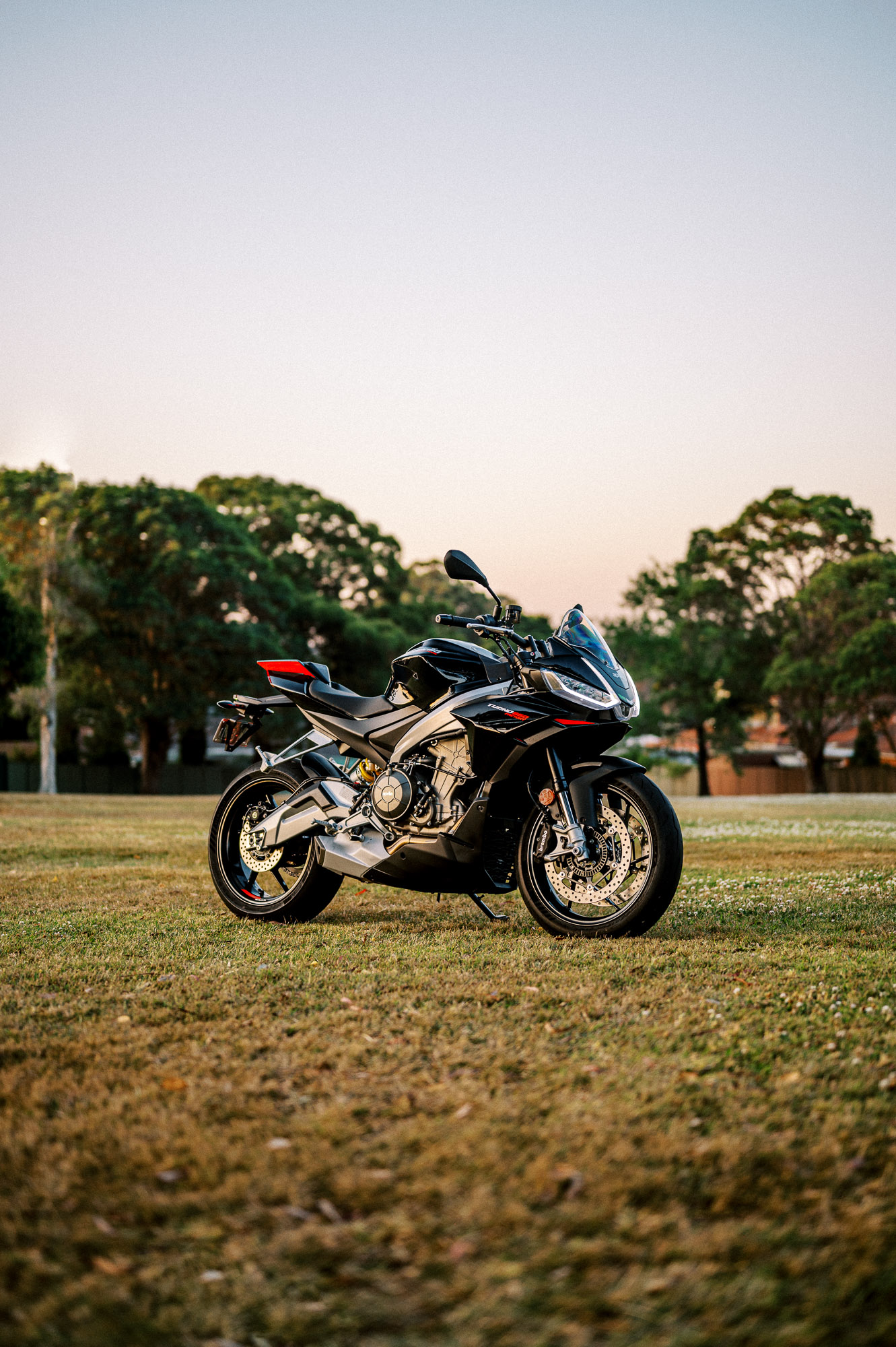 a 2023 Aprilia Tuono 660 Factory in a park at sunset