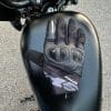 Back of the right hand resting on gas tank of bike