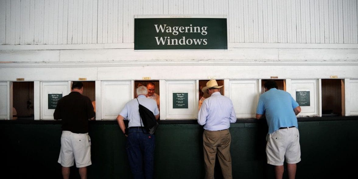 Four old men in front of six wagering windows.