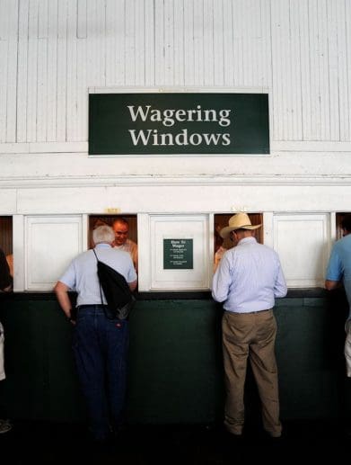 Four old men in front of six wagering windows.