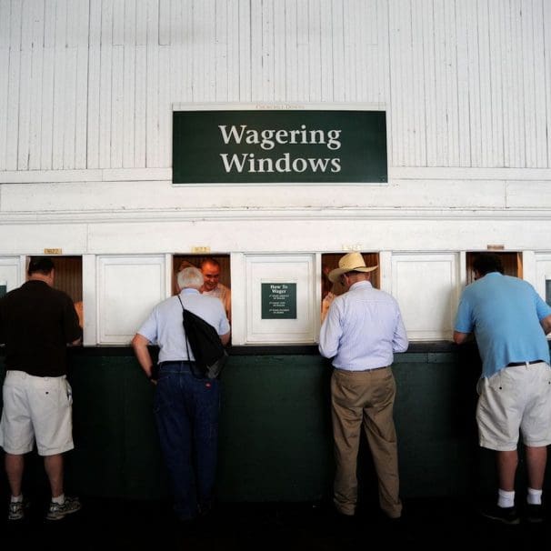 Four old men in front of six wagering windows.