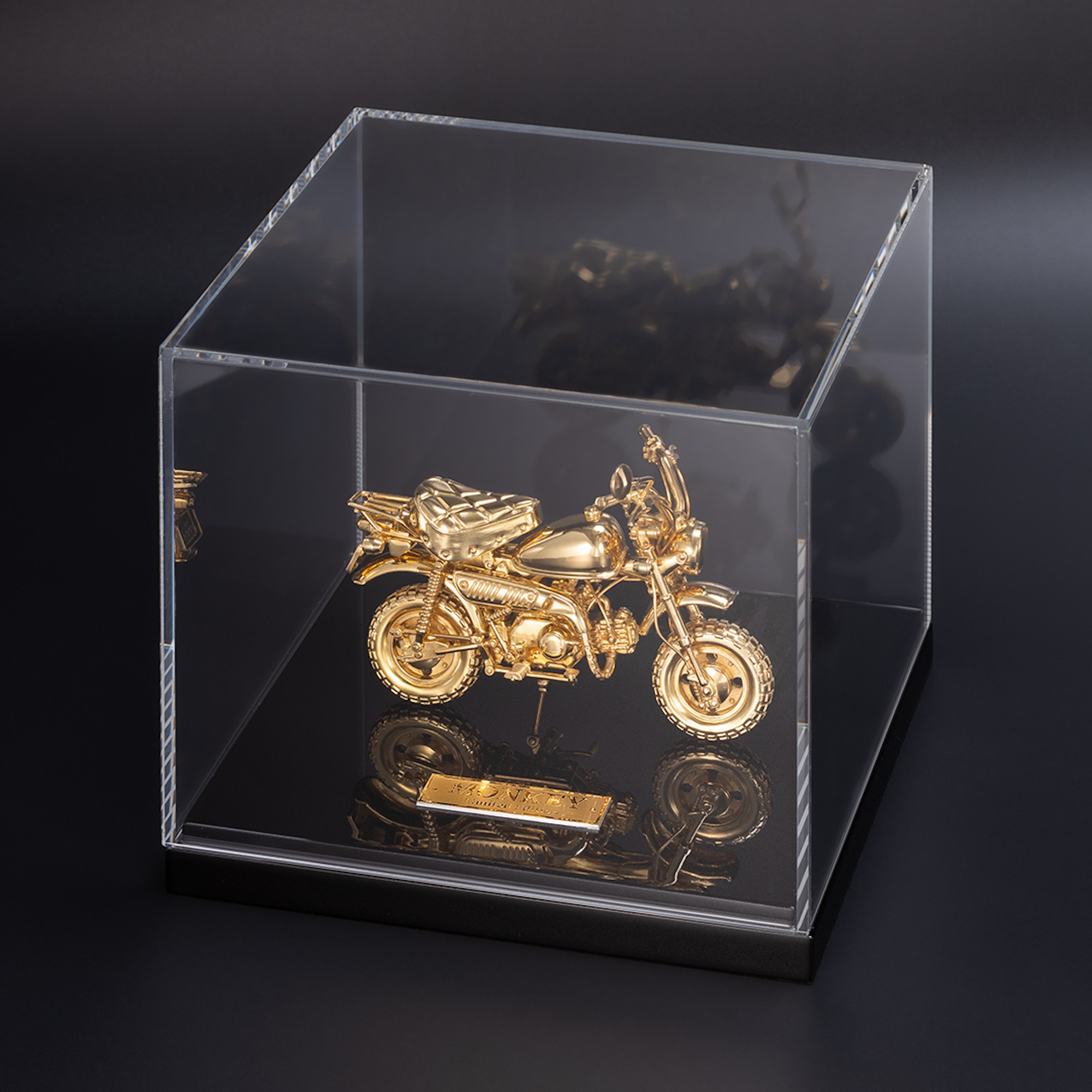 A gold motorcycle figurine in a viewing case.