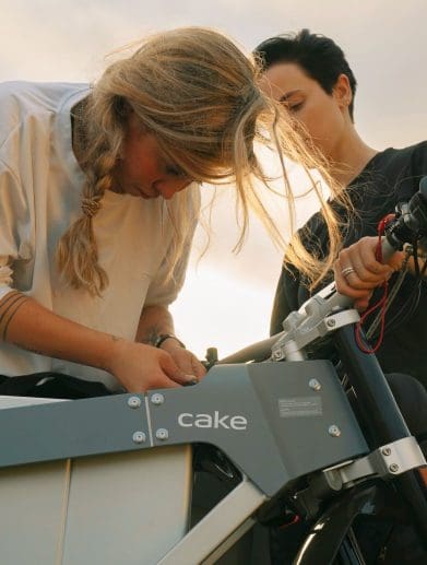 Two girls bending over an electric motorcycle.