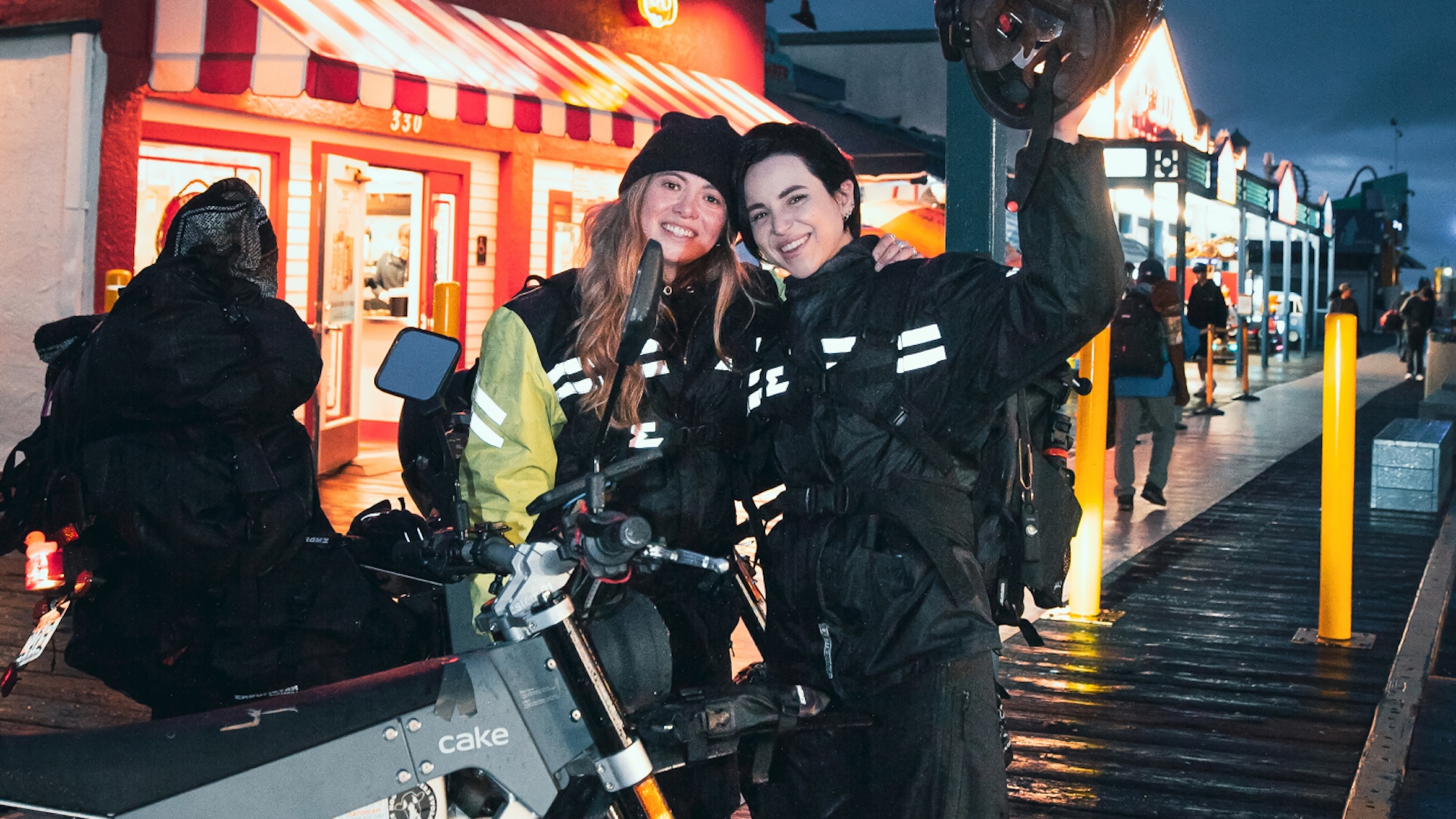 Two girls posing for a photo behind an electric motorcycle.