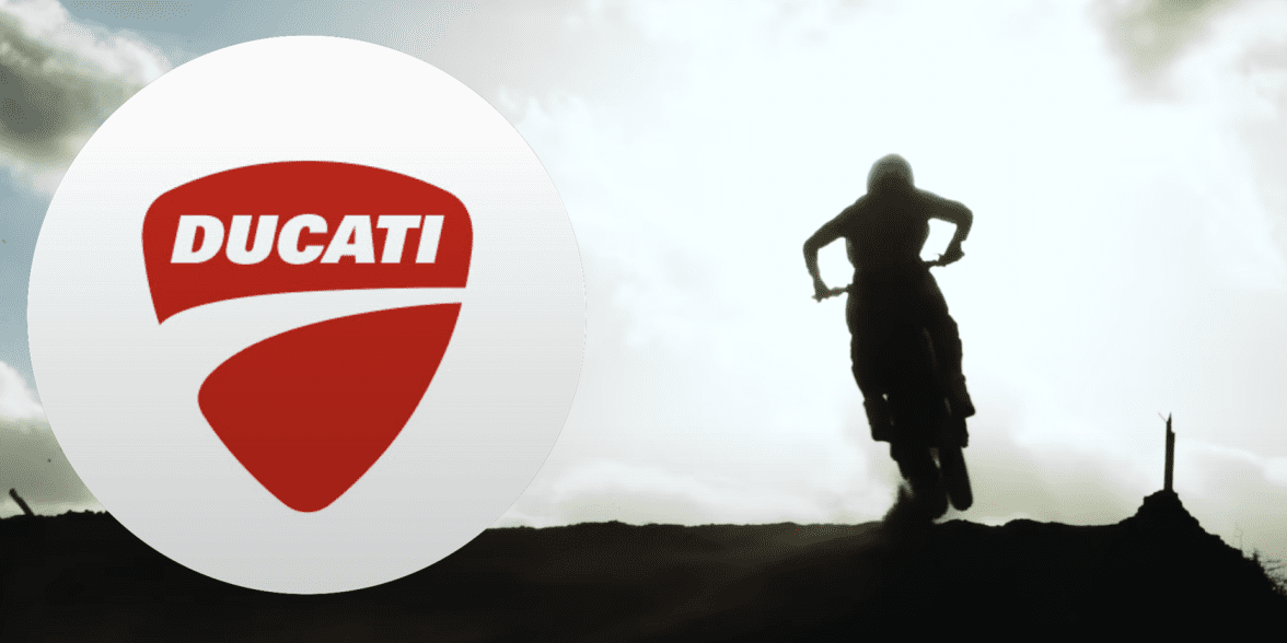 A view of a Ducati motocross motorcycle next to the brand's logo.