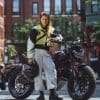 A woman standing in front of an electric motorcycle.