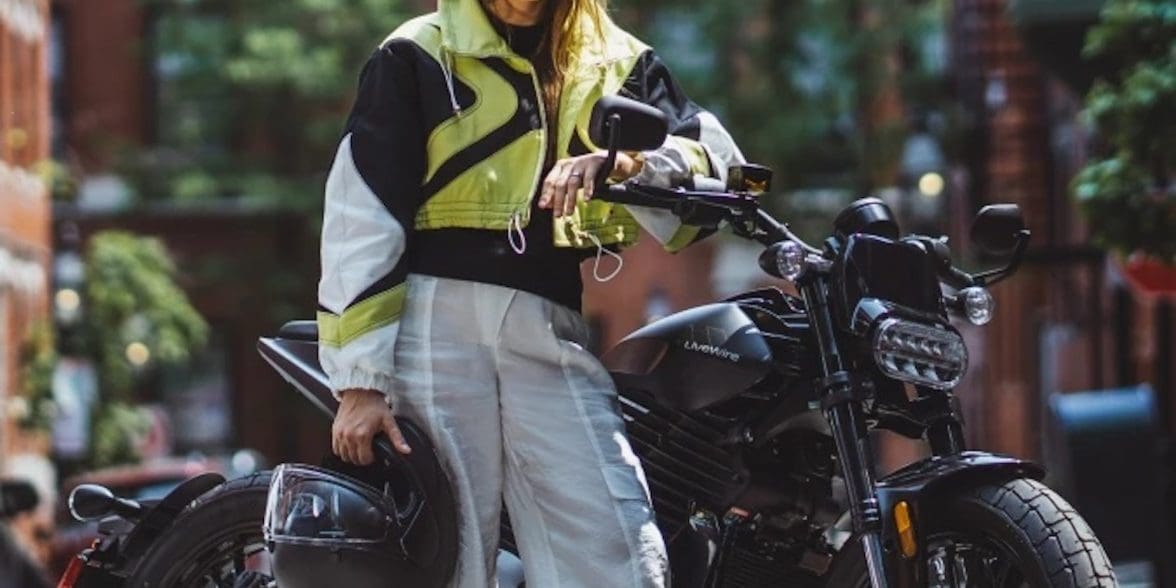 A woman standing in front of an electric motorcycle.