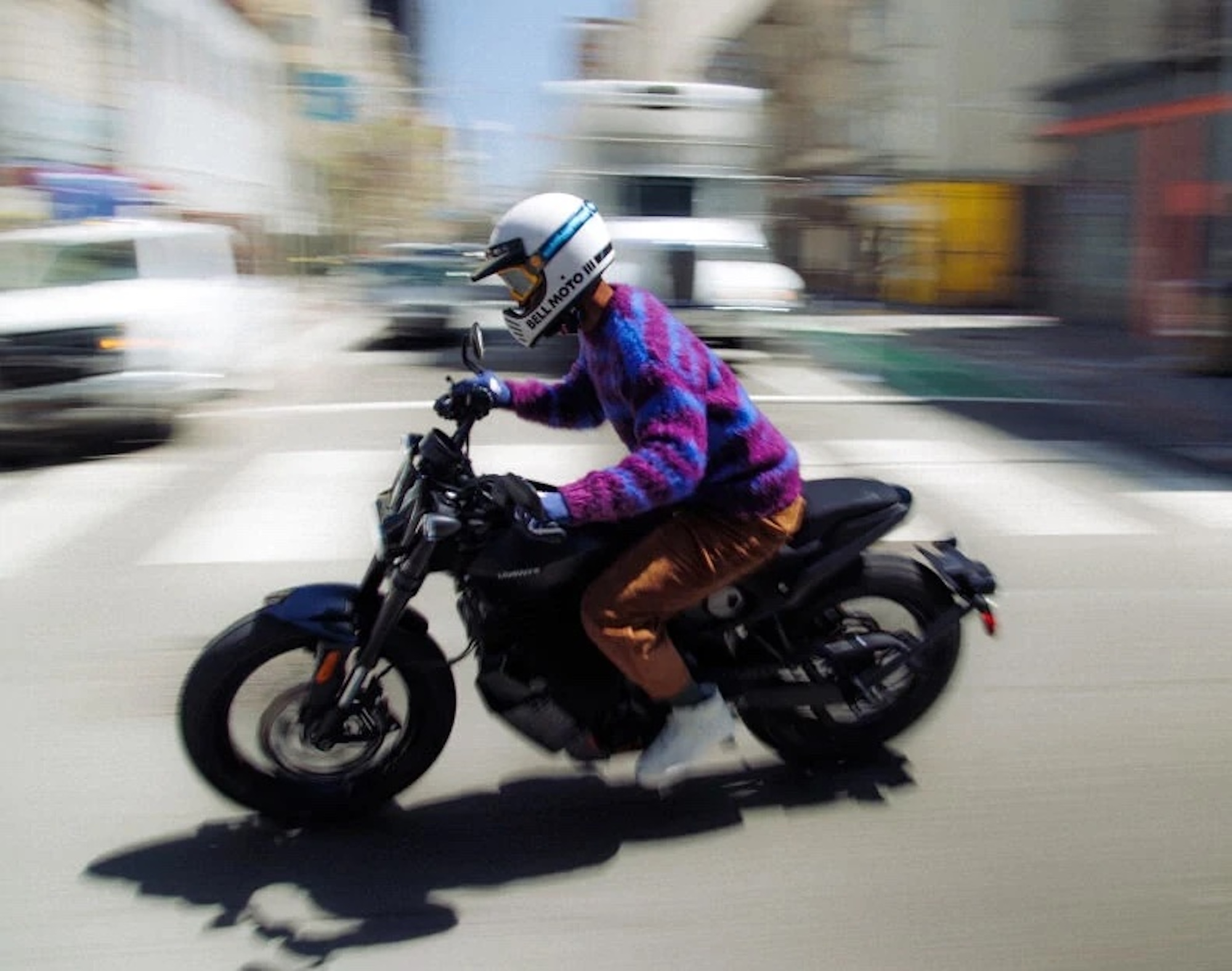 a rider crossing an intersection on an electric motorcycle.