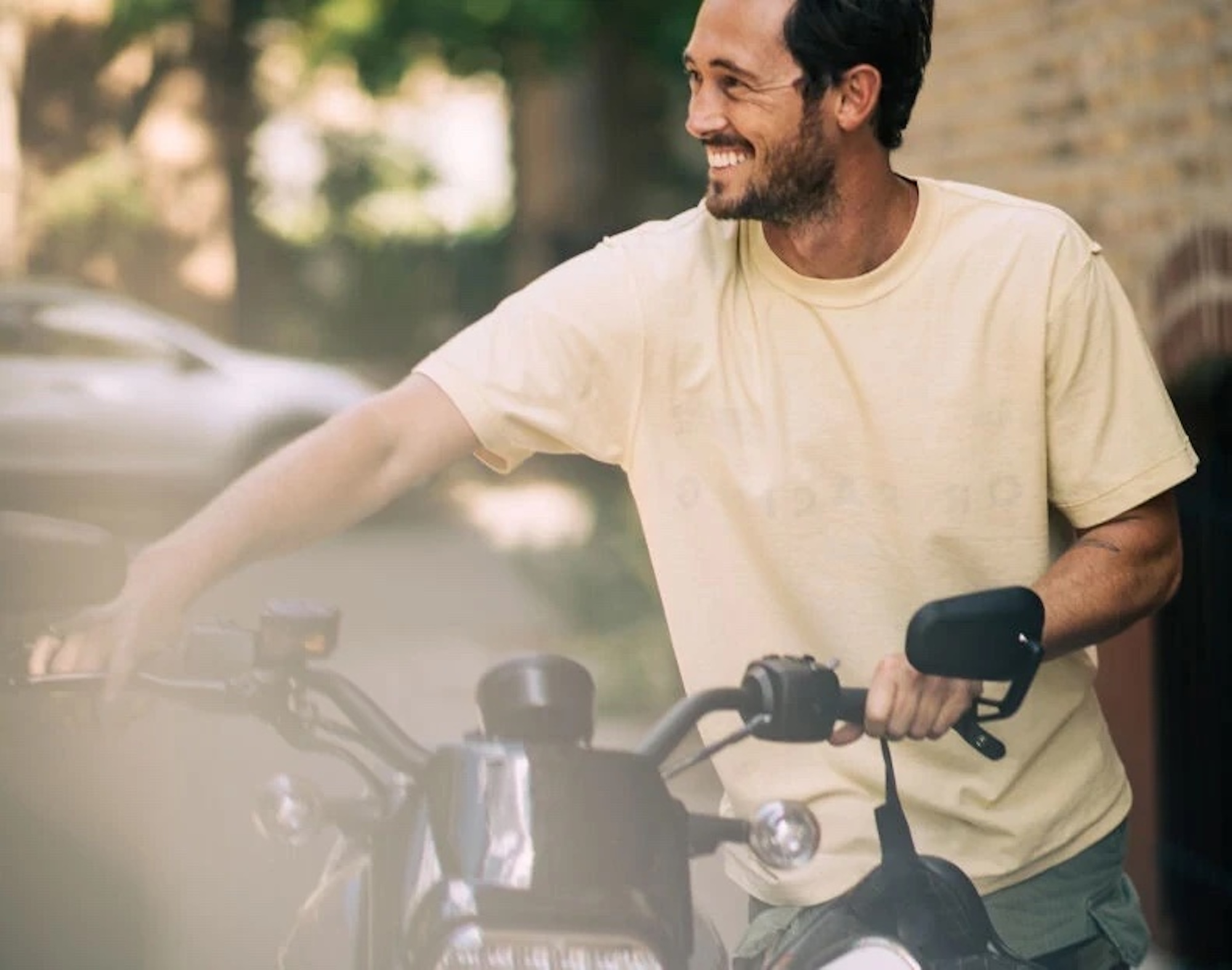 A man smiling while holding the bars of an electric motorcycle.