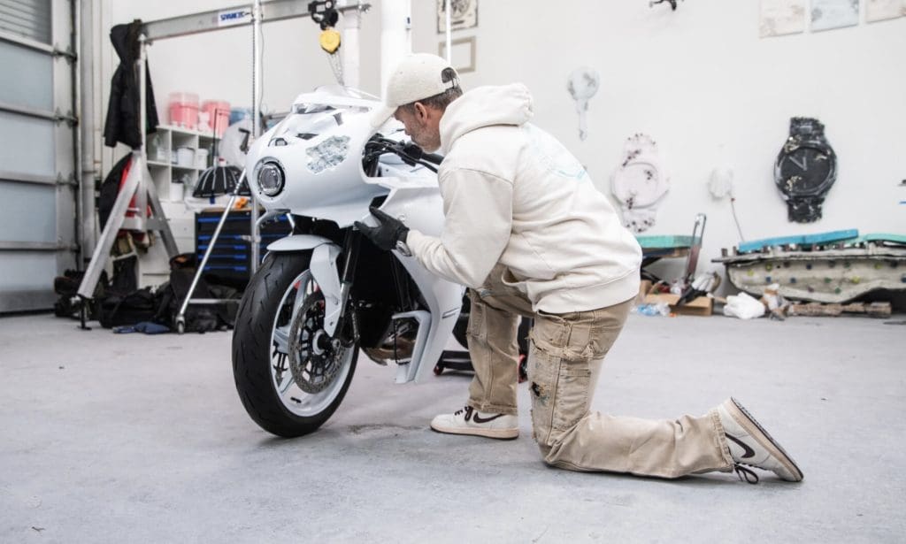 A person kneeling in front of a custom motorcycle.