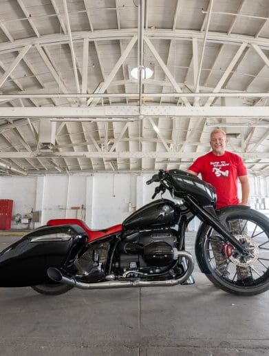 A side view of a hot rod motorcycle and the custom builder.