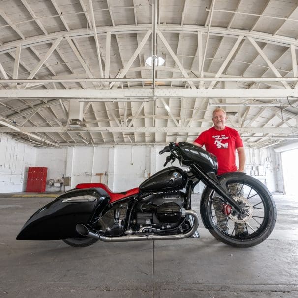 A side view of a hot rod motorcycle and the custom builder.