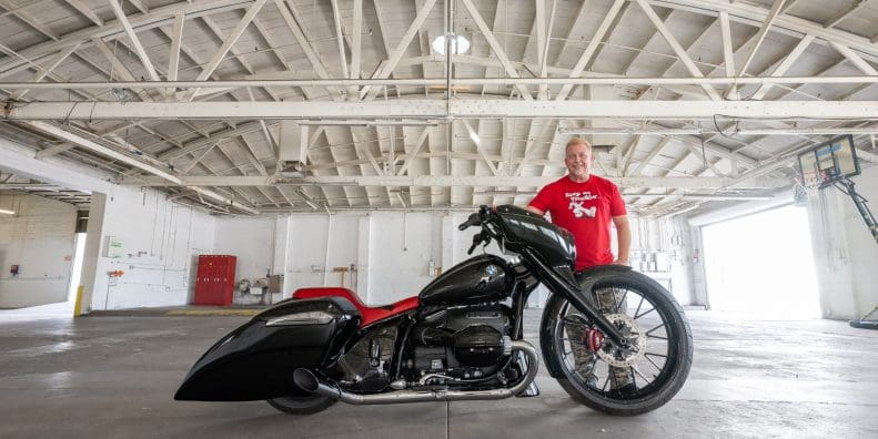 A side view of a hot rod motorcycle and the custom builder.