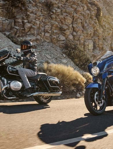 Two BMW motorcycles riding on a paved road.