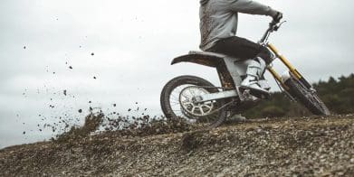 A motorcyclist riding an EV in the dirt.