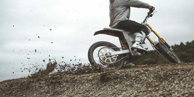 A motorcyclist riding an EV in the dirt.