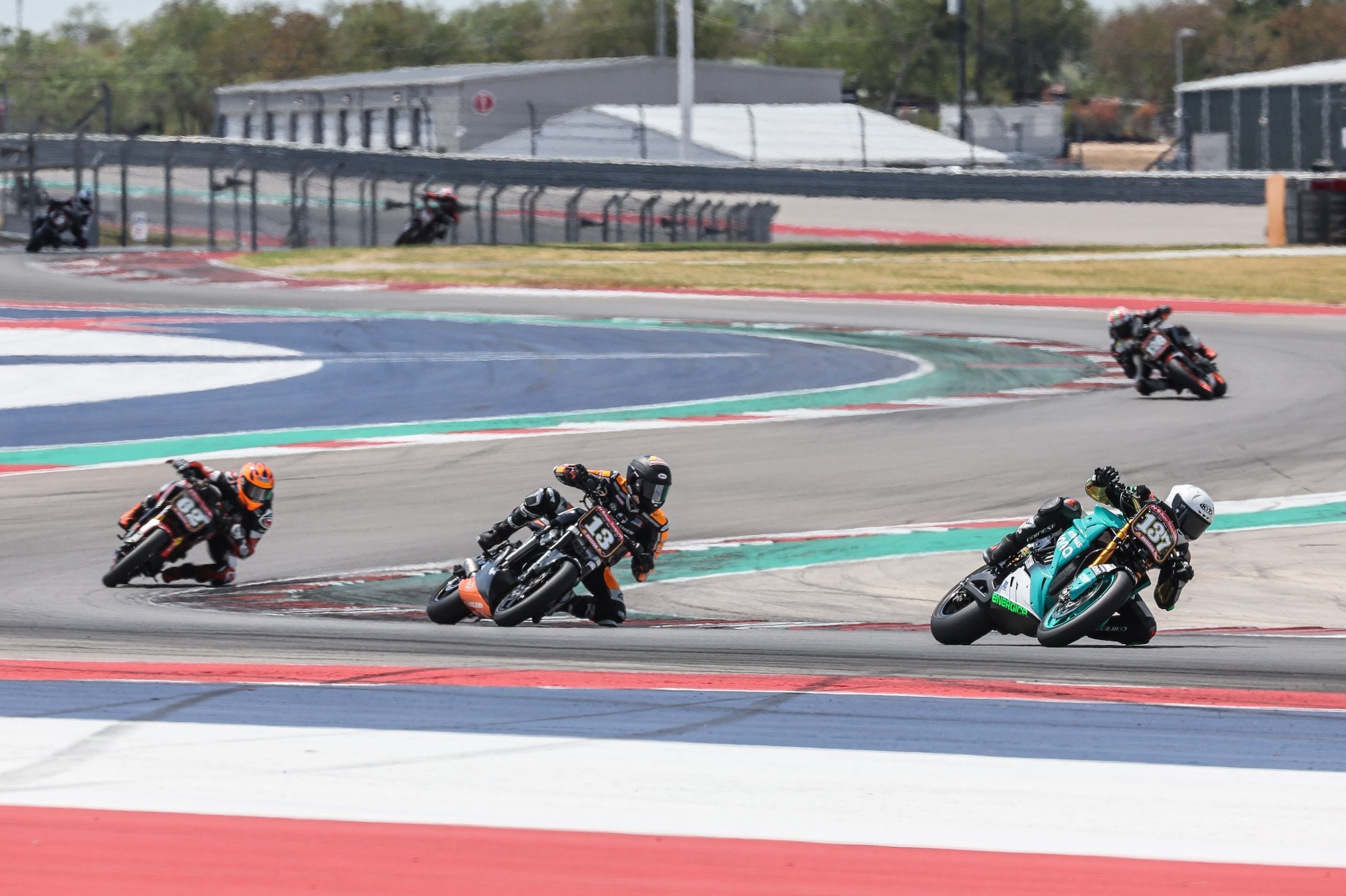 Three motorcycle riders racing around a track. 